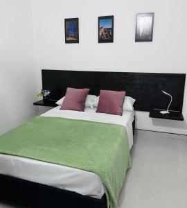 een slaapkamer met een groot bed en een groene deken bij Casa Cabieles Hostal in Yopal