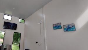 een witte kamer met drie foto's aan de muur bij Rancho Lyon Playa Costa Azul in Sonsonate
