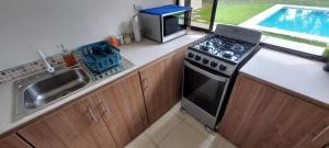 a kitchen with a stove top oven next to a sink at Rancho Lyon Playa Costa Azul in Sonsonate