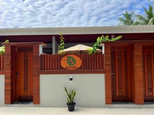 a house with a wooden fence and an umbrella at Dhonfalhu Dhigurah in Dhigurah
