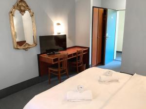 Habitación con 2 camas, escritorio y espejo. en Hotel Mozart Bonn en Bonn