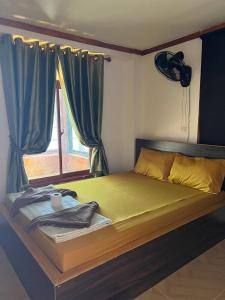 a bedroom with a bed with a window and a yellow bedspread at White Rose Guesthouse in Koh Rong Island