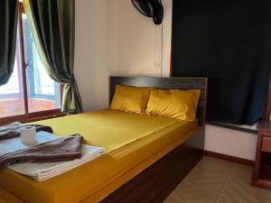 a bedroom with a bed with yellow sheets and a window at White Rose Guesthouse in Koh Rong Island