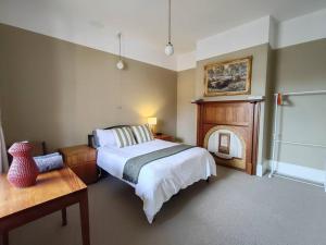 Melville Heritage Cottage, Hobart CBD في هوبارت: غرفة نوم بسرير ومدفأة