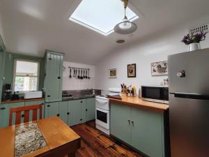 Melville Heritage Cottage, Hobart CBD في هوبارت: مطبخ به ثلاجة وطاولة بداخله
