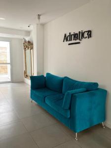 eine blaue Couch in einem Zimmer mit aania Schild an der Wand in der Unterkunft Adriatica Apartamentos in San Luis
