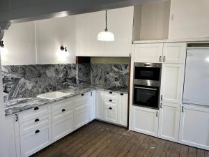 a kitchen with white cabinets and white appliances at Comfy Queenslander Cottage in Brisbane