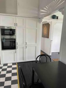 a kitchen with white cabinets and a checkered floor at Comfy Queenslander Cottage in Brisbane