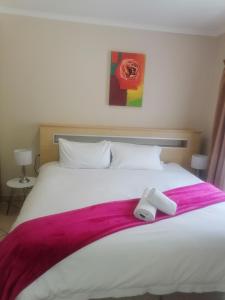 uma grande cama branca com um cobertor roxo em Repa Boutique Guest Lodge em Kimberley