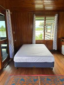 a bed in a room with two windows at Sunset View-Villa in Pacific Harbour