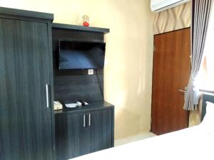 um quarto com um armário preto com uma televisão e uma porta em North Wing Canggu Resort em Dalung