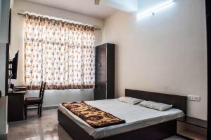 a bedroom with a bed and a chair and a window at Hotel Shivam in Ajmer