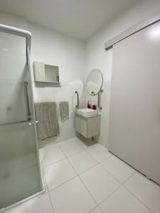 a white bathroom with a sink and a shower at Conforto na Praia do Pontal in Rio de Janeiro