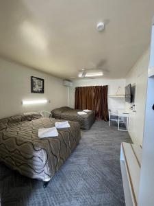 チャーターズ・タワーズにあるThe Park Motelのベッド2台とデスクが備わるホテルルームです。