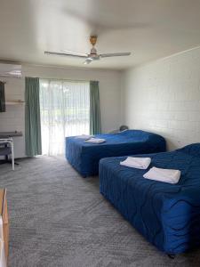 Habitación con 2 camas azules y ventana. en The Park Motel, en Charters Towers