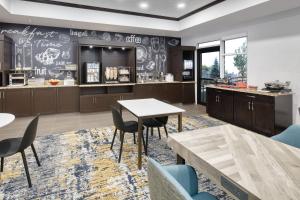 una cocina con mesas, sillas y una barra en TownePlace Suites by Marriott Sudbury, en Sudbury