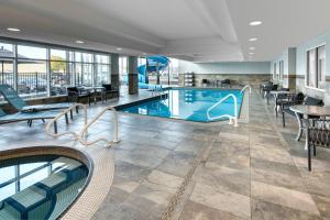 a pool in a hotel lobby with tables and chairs at TownePlace Suites by Marriott Sudbury in Sudbury