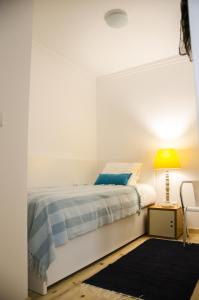 a white bedroom with a bed and a lamp at Pensao Sisudo in Sintra