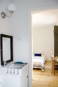 a white bedroom with a bed and a mirror at Pensao Sisudo in Sintra