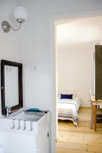 a white bedroom with a bed and a mirror at Pensao Sisudo in Sintra +4 photos