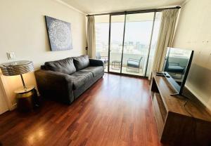 a living room with a leather couch and a large window at Arauco Premium Suite in Santiago