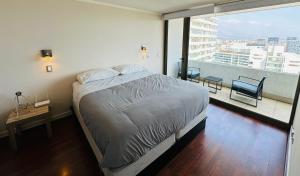 a bedroom with a bed and a desk and a large window at Arauco Premium Suite in Santiago