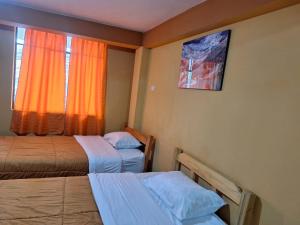 una camera d'albergo con due letti e una finestra di Montañero Hostel II a Huaraz