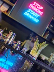 een bar met glazen op een aanrecht met een neonbord bij THE TIMES HOTEL in Angeles