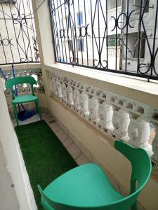 a balcony with two green chairs and a window at Jackie homes in Mombasa