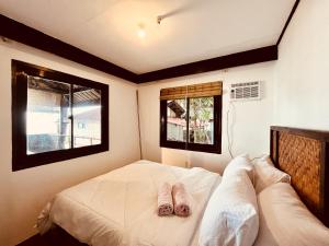 a bedroom with two pairs of slippers on a bed at Villa Milagros Dive Inn Anilao in Mabini
