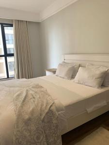 ナイロビにあるApple Tree Apartment - 3beds -3Bedroom - 4 Washroomの白い枕と窓が備わる白いベッド
