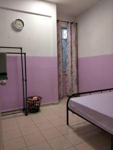 1 dormitorio con 1 cama y reloj en la pared en SinggahSana Homestay Pasir Mas, en Pasir Mas