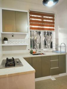 una cocina con fregadero y una ventana. en SinggahSana Homestay Pasir Mas, en Pasir Mas