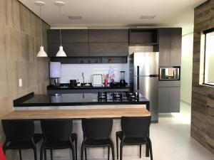 a kitchen with a counter with chairs and a refrigerator at Apartamento completo em Caruaru - 2 quartos - Conforto e ótima localização para famílias in Caruaru