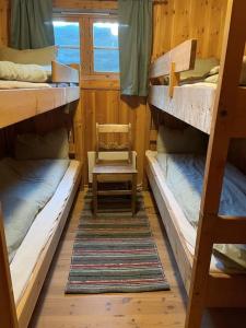 a room with three bunk beds and a chair at Stallen - koselig lite hus på gårdstun in Skjåk