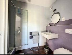 een paarse badkamer met een wastafel en een douche bij La Cour de Grandmenil in Manhay