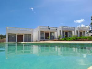 a large swimming pool in front of a house at Cave Diani Holiday Apartments in Diani Beach
