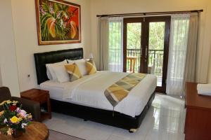 a bedroom with a large bed and a balcony at Guesthouse Gusti Putu Oka in Ubud