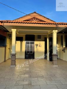 a house with a gate and a patio at Zya'S Homestay Gong Badak in Kampong Bukit Berangan