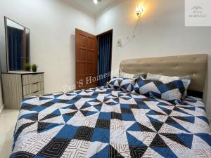 een slaapkamer met een bed met een blauwe en witte quilt bij Zya'S Homestay Gong Badak in Kampong Bukit Berangan