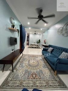 a living room with a blue couch and a table at Zya'S Homestay Gong Badak in Kampong Bukit Berangan