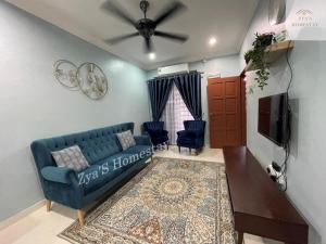 a living room with a blue couch and a tv at Zya'S Homestay Gong Badak in Kampong Bukit Berangan