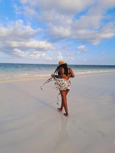 a woman standing on the beach holding a kite at Cave Diani Holiday Apartments in Diani Beach
