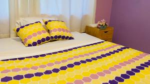 Una cama con almohadas amarillas y moradas. en Departamento vacacional en Puyo en Puyo