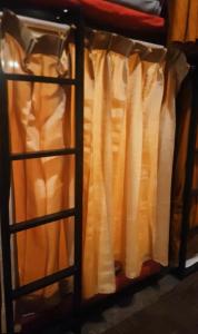 1 cama con cortinas naranjas en una habitación en Rubikz Hostel & Cafe, en Surabaya