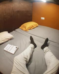 een persoon die op een bed ligt met zijn voeten erop bij Rubikz Hostel & Cafe in Surabaya