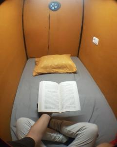 een persoon die op een bed een boek leest bij Rubikz Hostel & Cafe in Surabaya