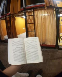 un libro abierto sentado en el suelo junto a una cama en Rubikz Hostel & Cafe, en Surabaya
