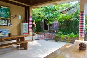 a room with a table and benches and a garden at Guesthouse Gusti Putu Oka in Ubud