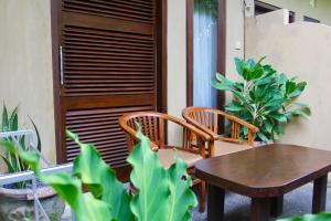 a patio with two chairs and a table and some plants at Guesthouse Gusti Putu Oka in Ubud